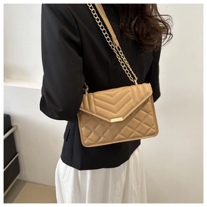 Detailed view of khaki quilted chain crossbody bag on model for size and fit reference