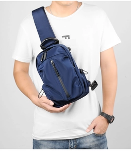 Detail of dark blue nylon chest bag showing multiple zippers and adjustable strap