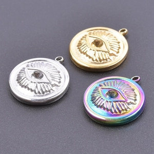 Macro shot of evil eye pendants in silver, gold, and iridescent steel on dark background