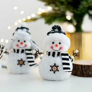 Christmas snowman plush doll with striped scarf and plaid hat on festive bokeh background