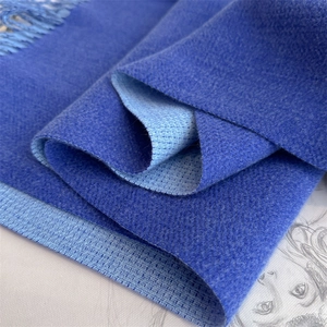 Detail of dual-sided blue cashmere-like scarf showing texture and fringed edges