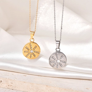 Close-up of gold and silver sunburst pendant necklaces on white silk and stone base