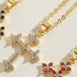 Detail of cross pendant necklace with colorful zircon stones in gold plated setting