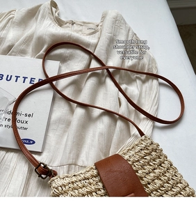 Detail view of woven paper straw bag with brown leather strap and buckle closure