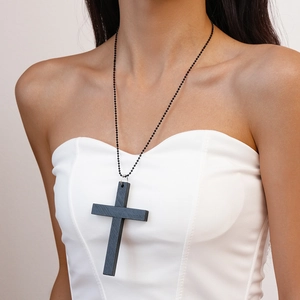 Gros plan d'un pendentif croix noire en bois avec une fine chaîne à perles