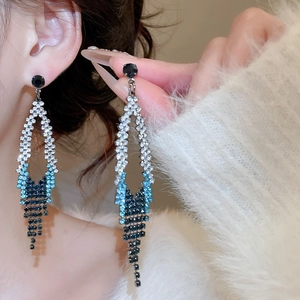 Gros plan de boucles d'oreilles pendantes à strass bleus dégradés avec forme de losange