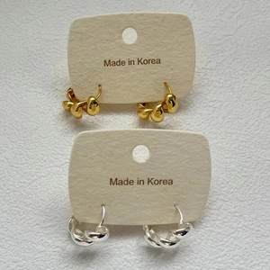 Macro detail of gold and silver twisted hoop earrings on jewelry display cards