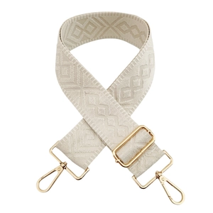 Close-up of beige adjustable woven bag strap with diamond pattern and gold metal hardware