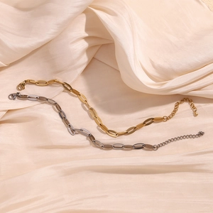 Polished gold and silver stainless steel cable chains with lobster clasps on silk fabric