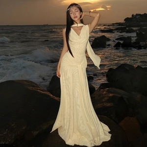 Close-up of elegant cream backless mesh dress with halter neck on seaside rocks at sunset