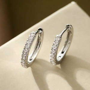 Minimalist silver copper earrings with cubic zirconia stones on a beige background