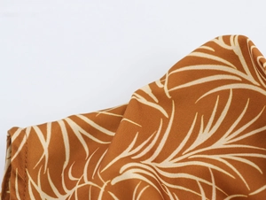 Detail of vacation dress fabric featuring white coconut tree prints on a brown base