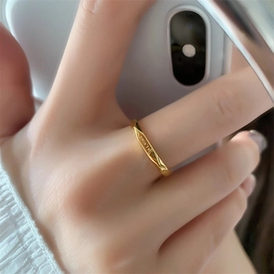 Close-up of golden Mobius twist ring featuring delicate engraved lettering on the surface