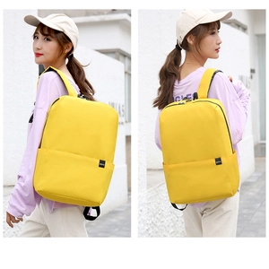 Outdoor shot showing a person wearing a lightweight yellow nylon backpack from a rear view