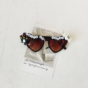 Detail of heart-shaped Halloween kids sunglasses with Trick or Treat letter beads and ghost decor