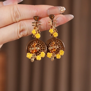 Dettaglio di orecchini a liuto vintage con fiori smaltati e strass color ambra