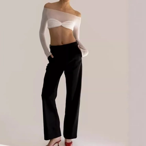Detail of off-shoulder white mesh top paired with high-waisted black wide-leg trousers