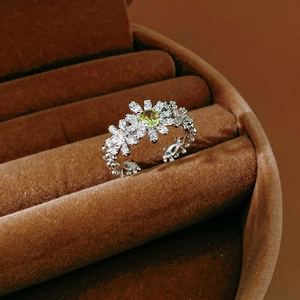 Macro shot of silver ring with olive green zircon flower and white diamond pavé detail