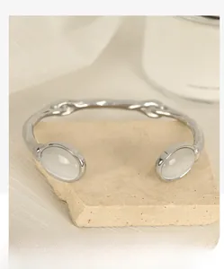 Detail of silver hammer textured open cuff with two oval opalescent stones on stone base