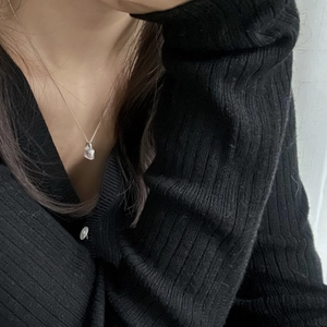 Close-up of minimalist 925 silver necklace with mini zircon lock pendant on black knit