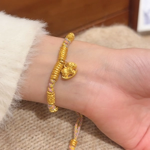 Detail of woven multicolor cord bracelet with gold beads and a cute elephant charm