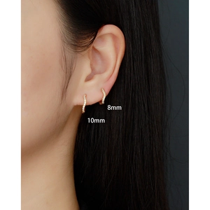Pair of gold pavé hoop earrings in 8mm and 10mm sizes shown on a model's ear