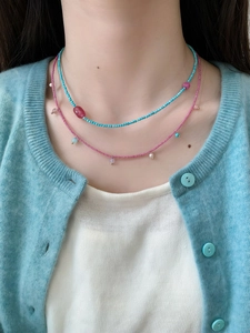 Close-up of a double-layered beaded necklace with turquoise and pink natural stones on a model