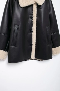 Detailed view of the button closure and shearling trim on black faux leather coat