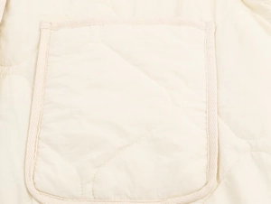 Detail of diamond quilted pocket and soft fabric texture on cream puffer jacket