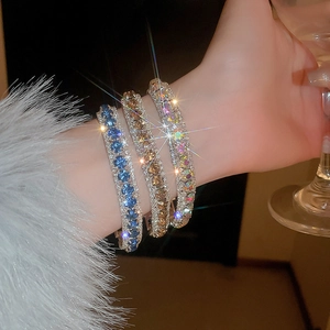 Close-up of three sparkling wide rhinestone bracelets in blue, champagne and aurora white