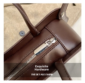 Close-up of polished metal zipper and handle hardware on a brown leather handbag