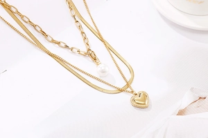 Vue détaillée du collier triple rang doré avec perle baroque et pendentif cœur 3D