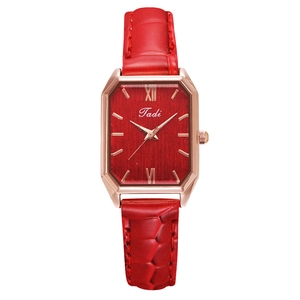 Detail of red croc-pattern leather strap and rectangular rose gold quartz watch dial