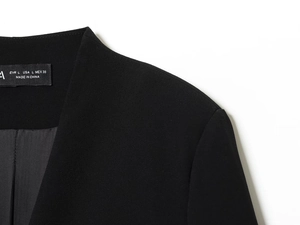 Detail of a black blazer dress collar showing fabric texture and L-size tag on white background