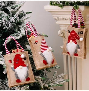 Three burlap Christmas gift bags with gnome patterns hung by a white fireplace