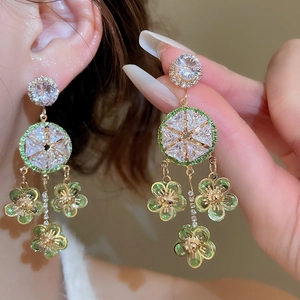 Detail view of emerald green flower tassel earrings with zircons on gold alloy