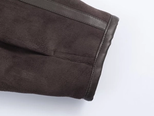 Close-up of suede fabric stitching with dark brown leather trim on the jacket cuff