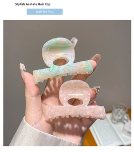 Detail of marble pattern acetate hair claws in green and pink with gold lettering