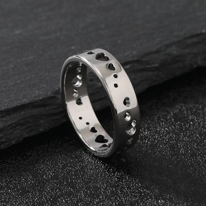 Polished silver stainless steel ring with heart cutouts on black stone surface