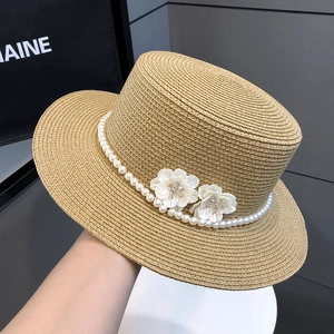 Detail of straw boater hat with elegant pearl band and white 3D floral decorations