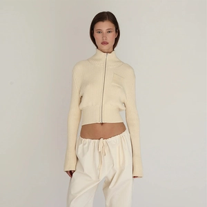 Close-up of the ribbed knit texture and zipper detail on the beige cropped cardigan