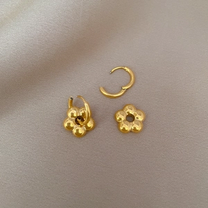 Polished gold flower pendant hoop earrings in titanium steel on soft fabric