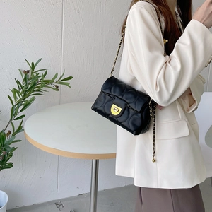 Classic black quilted chain bag with gold hardware worn by a model in a cafe