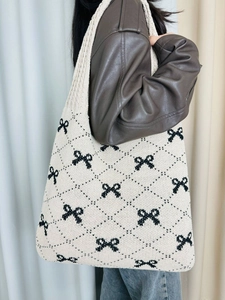 Detail of knitted tote bag with black bow patterns and soft diamond texture weave