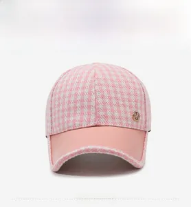 Détail de la casquette pied-de-poule rose avec emblème en métal doré et strass brillants