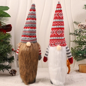 Close-up of red and grey knitted Christmas gnomes with plush beards and festive pine decor