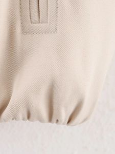 Detailed close-up showing the premium beige twill woven fabric and fine stitching of the jacket