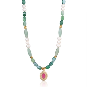 Dettaglio collana di perle boho con pietre verdi e ciondolo dorato con gemma magenta
