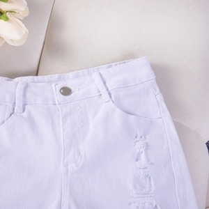 Dettaglio di pantaloncini di jeans bianchi con effetto strappato e bottone in metallo lucido