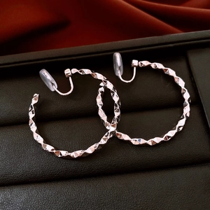 Close-up of silver geometric faceted hoop earrings on velvet with clip-on backings